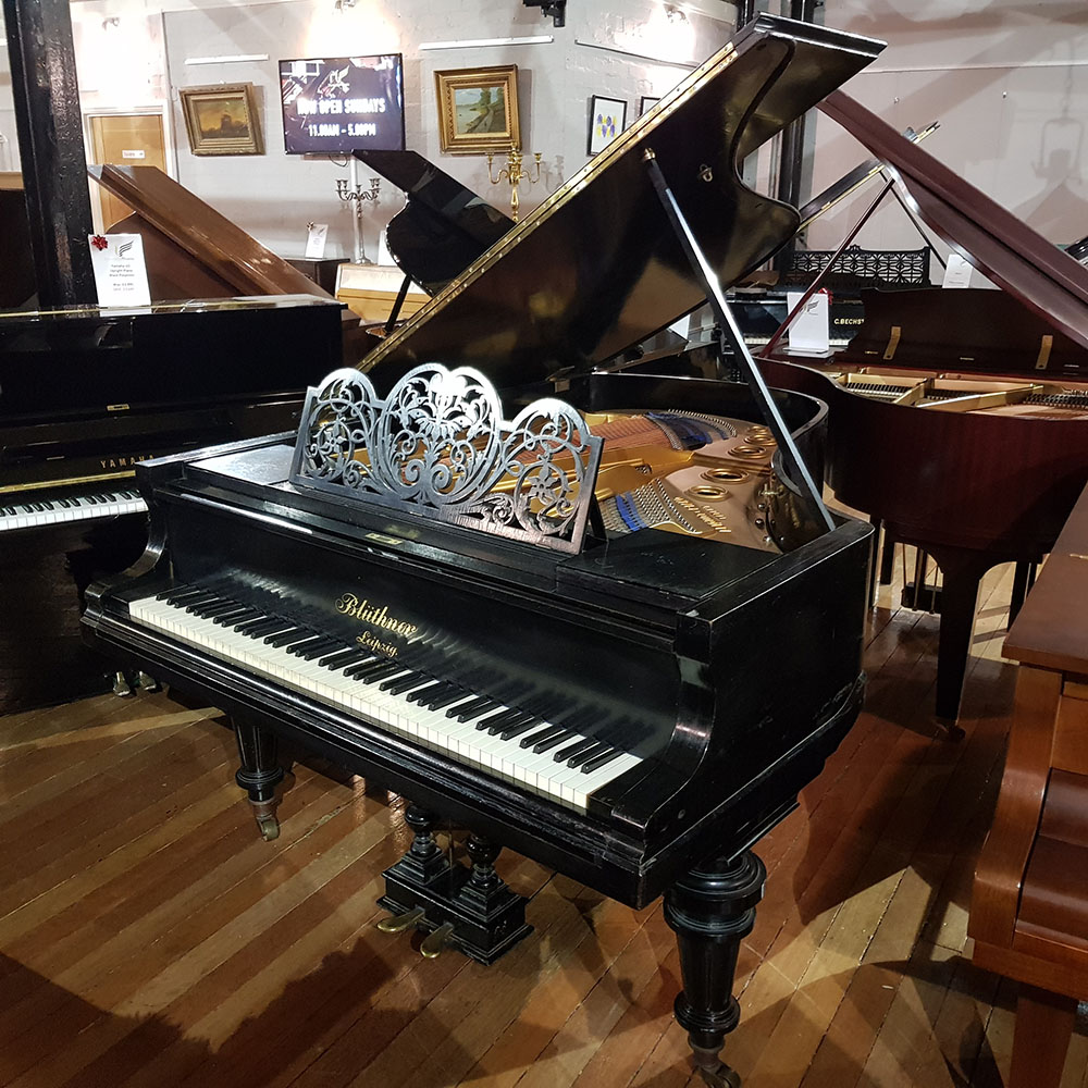 Used Bluthner grand piano in a black case for sale.